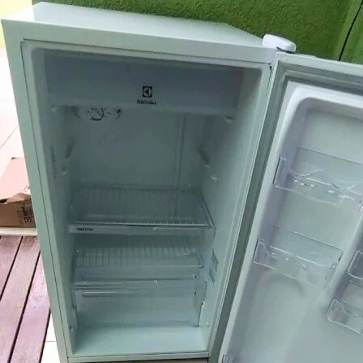 Interior de geladeira Electrolux branca aberta e higienizada após serviço de manutenção bem-sucedido.