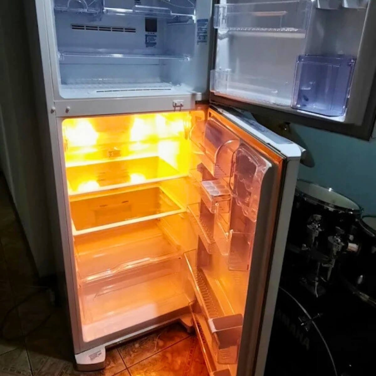 Geladeira duplex aberta com iluminação interna funcionando perfeitamente após reparo na parte elétrica.