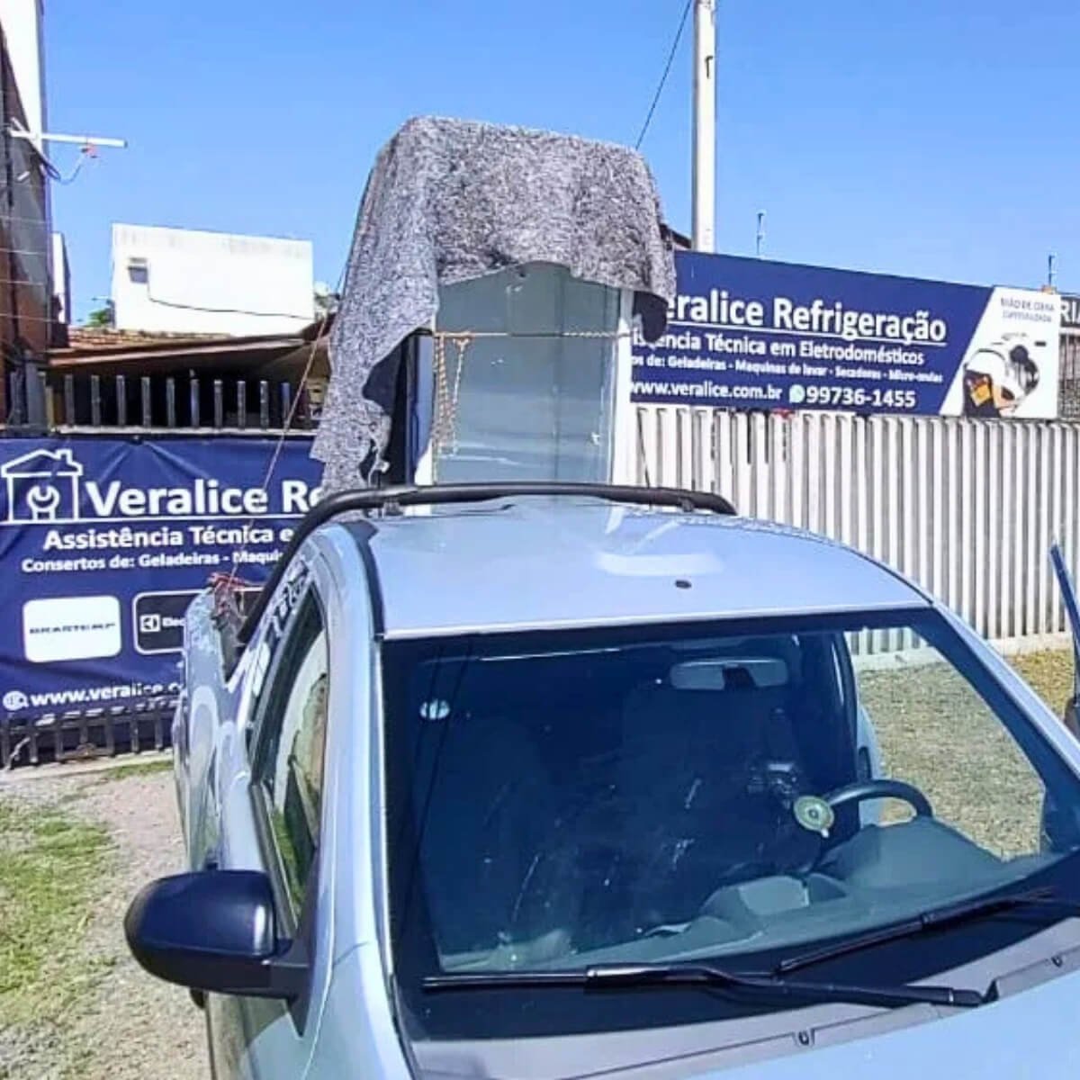 Veículo da assistência técnica Veralice Refrigeração transportando geladeira em frente à sede da empresa em Curitiba.