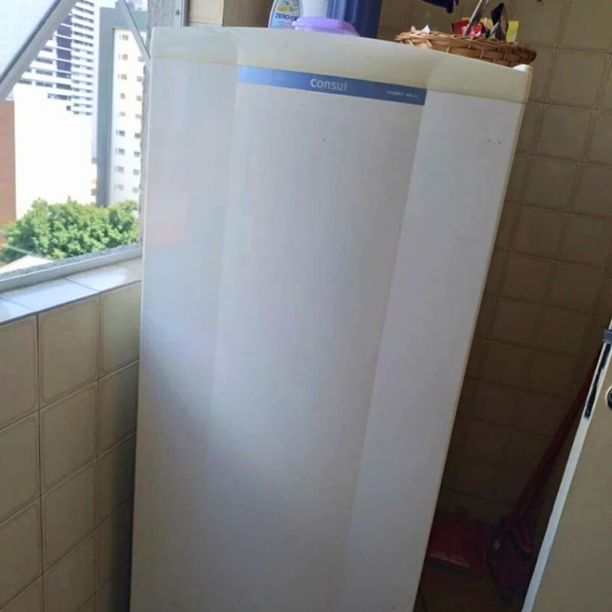 Freezer vertical Electrolux branco em área de serviço após recarga de gás refrigerante.